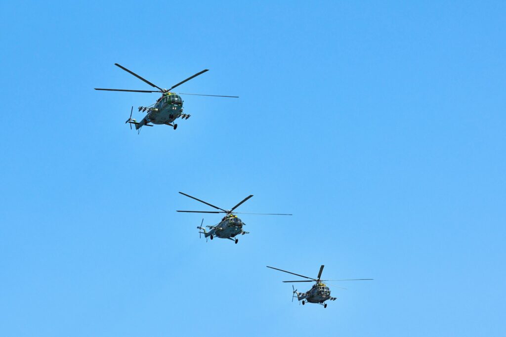 Three military helicopters flying in blue sky performing demonstration flight, air show, copy space